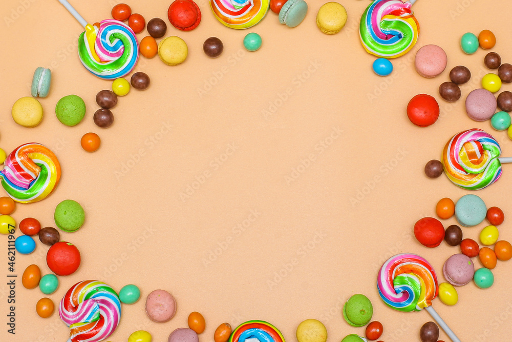 Blank circular frame made with various of colorful candy on cream background. Flat lay, top view