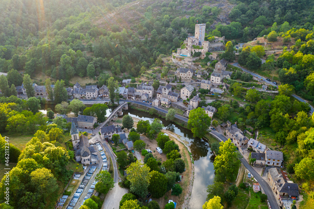 Aerial view of French village of Belcastel with stone arched bridge over Aveyron river and ancient castle on hill in summer