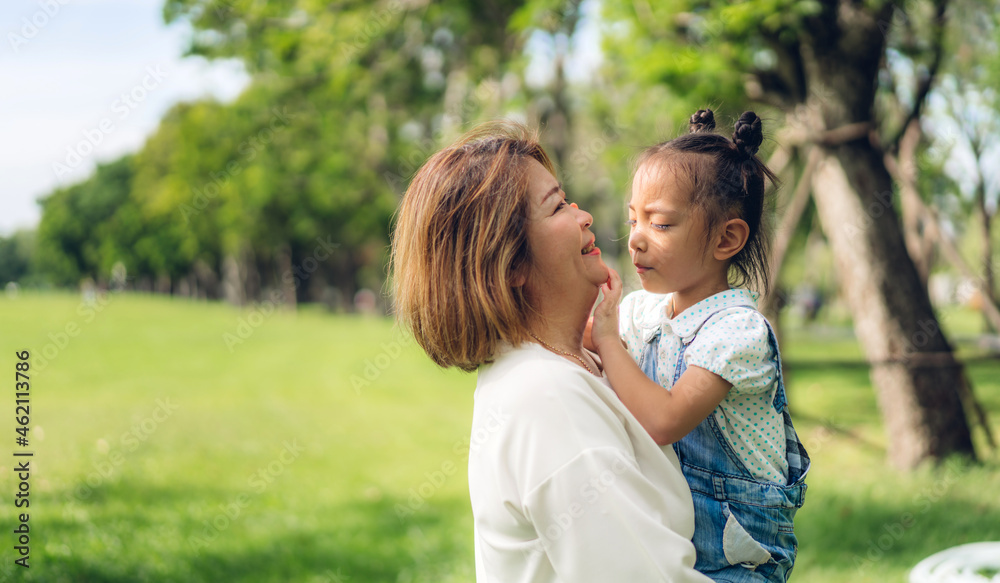 Portrait of happy love asian grandmother and little asian cute girl enjoy relax in summer park.Young girl with their laughing grandparent smiling together.Family and togetherness Portrait of happy love asian grandmother and little asian cute girl enjoy relax in summer park.Young girl with their laughing grandparent smiling together.Family and togetherness