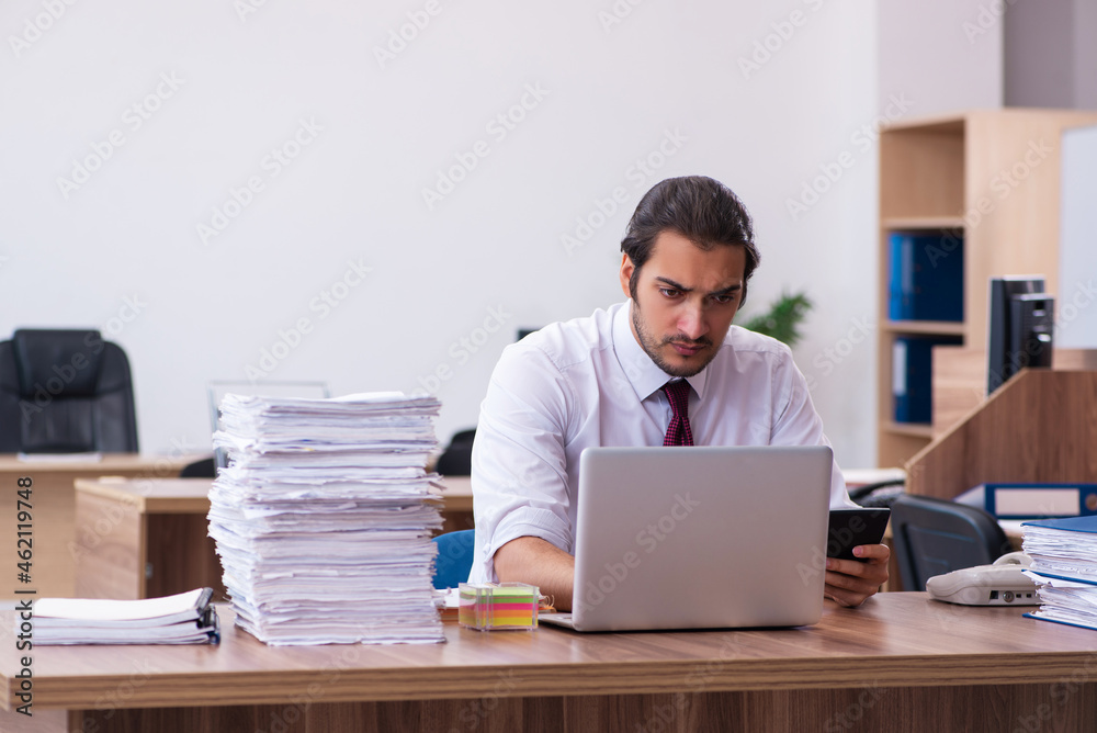 Young male bookkeeper unhappy with excessive work in the office Young male bookkeeper unhappy with excessive work in the office