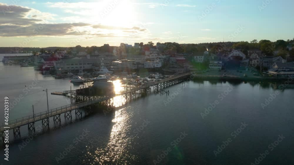 Small town of Boothbay, Maine with long footbridge during golden sunset with water reflection. Aerial view Small town of Boothbay, Maine with long footbridge during golden sunset with water reflection. Aerial view