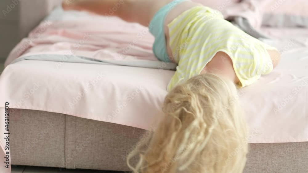 Portrait handsome cute little blonde girl having fun in bed in the morning. Adorable kid spinning, laughing, lying upside down. Portrait handsome cute little blonde girl having fun in bed in the morning. Adorable kid spinning, laughing, lying upside down.