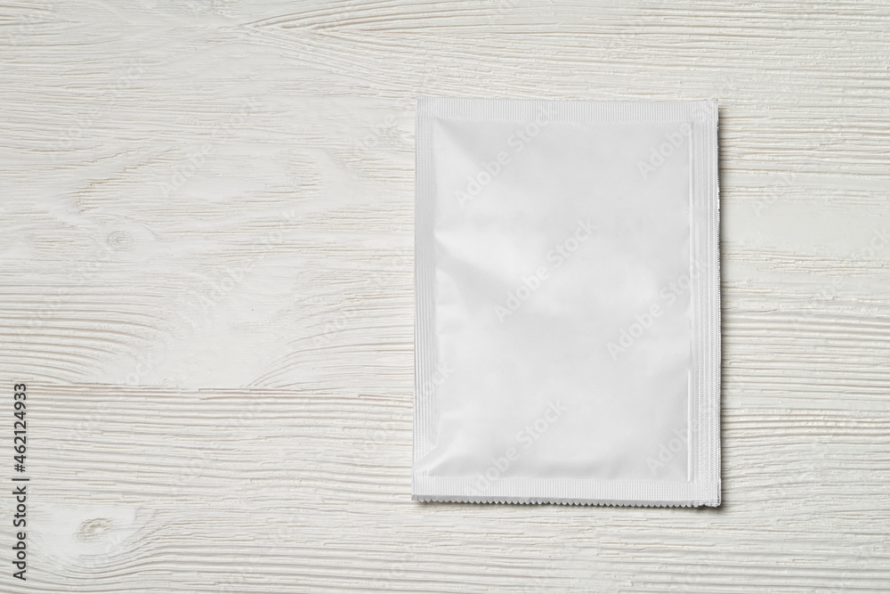 White paper sachet packet on wood table. White paper sachet packet on wood table.