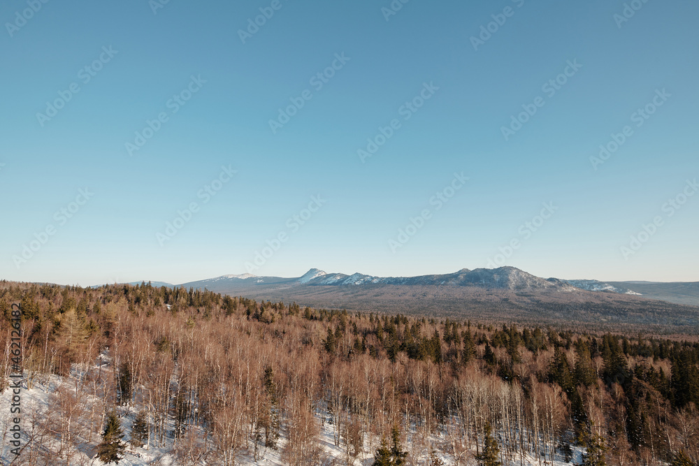 Scenery of landscape with blue sky, mountains and forest on frosty winter day