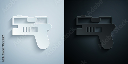 Paper cut Futuristic space gun blaster icon isolated on grey and black background. Laser Handgun. Alien Weapon. Paper art style. Vector