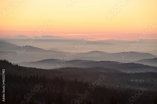 Majestic scenery of pink and yellow sky and mountains covered with forest at dawn