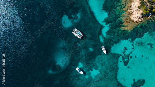Secret beach with clear water perfect for romantic vacation. Sailboats and catamarans anchor in the small bay. Paradise scuba divers. Drone aerial view, north Sardinia, Italy.