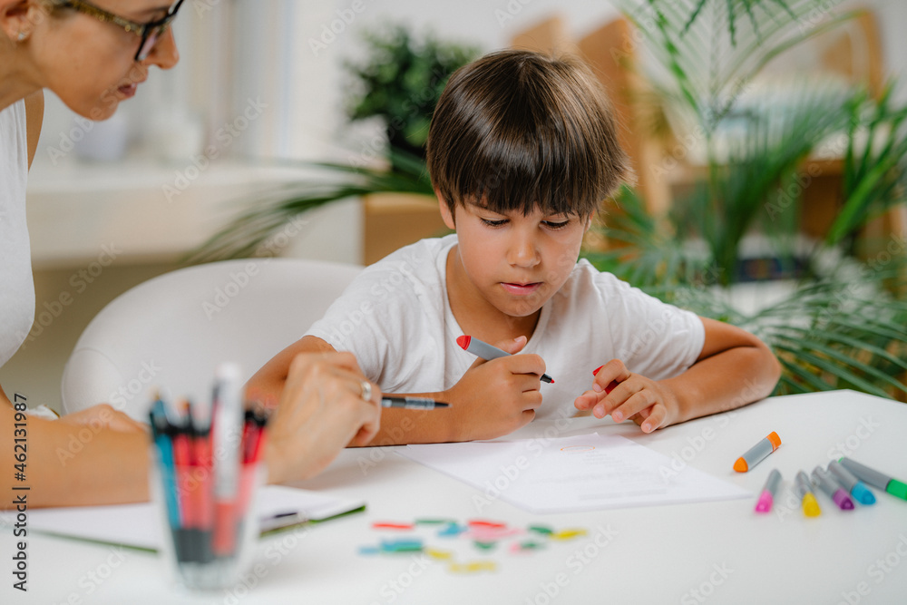 Preschool boy doing school education assessment test. Psychologist asking a questions and preschool boy writing answers. Preschool boy doing school education assessment test. Psychologist asking a questions and preschool boy writing answers.
