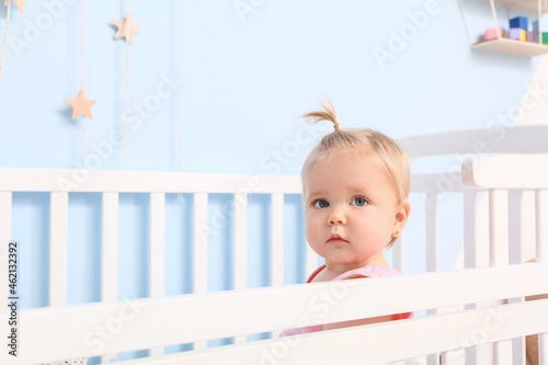 Cute baby girl in cot at home