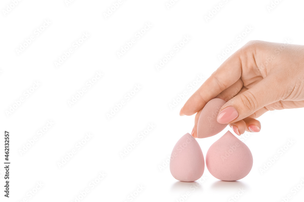 Female hand with stylish makeup sponges on white background