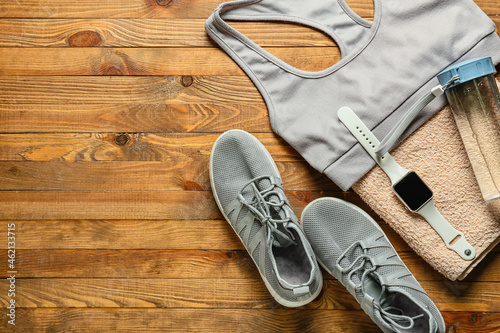 Sports top, shoes, bottle for water, towel and smartwatch on wooden background