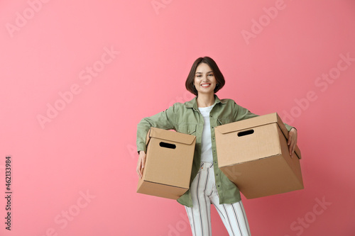 Young woman with wardrobe boxes on color background © Pixel-Shot