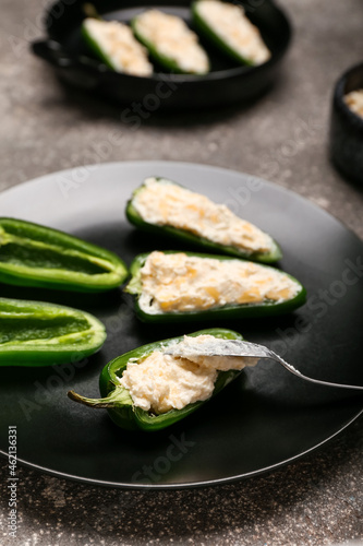 Plate with uncooked jalapeno poppers on grey background, closeup