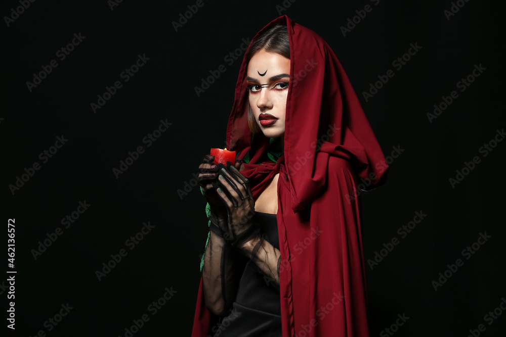 Young witch with candle on dark background Young witch with candle on dark background