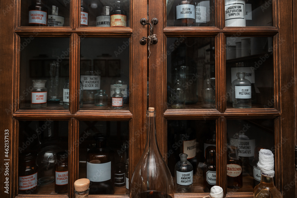 Empty scent bottles in old pharmacy. Wooden antique cupboard for medical drug storage