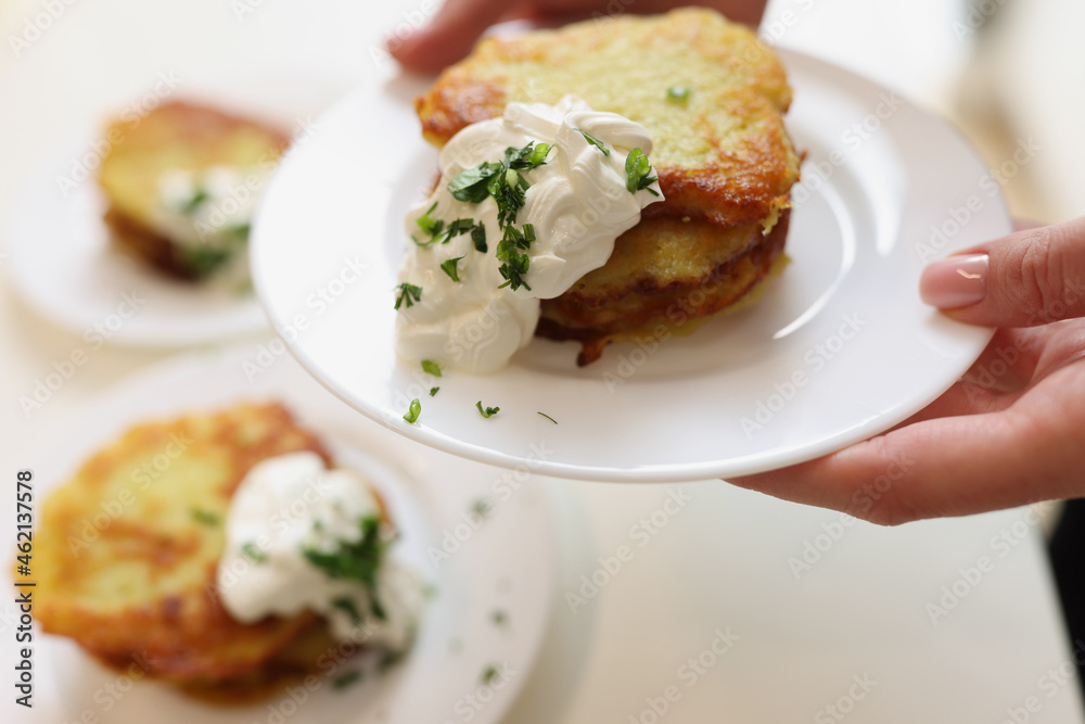 Potato pancakes with sour cream and herbs on plate