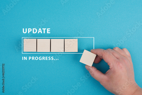 The words update in progress are standing beside the loading bar, hand puts last cube to the upload, blue colored background