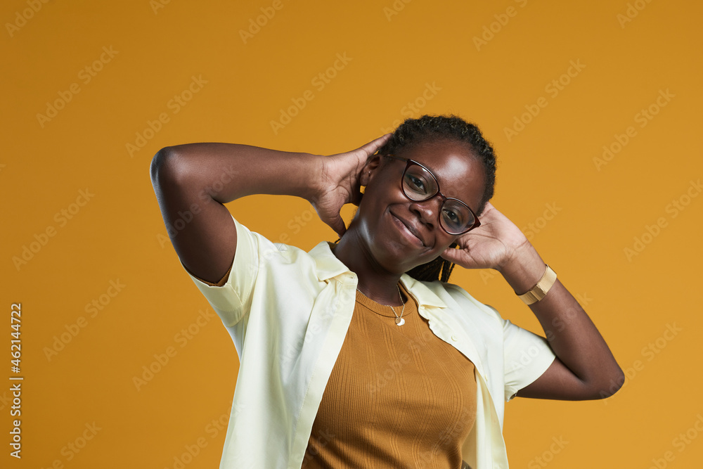 Portrait of carefree African-American woman looking at camera and smiling while posing against yellow background in studio, copy space Portrait of carefree African-American woman looking at camera and smiling while posing against yellow background in studio, copy space