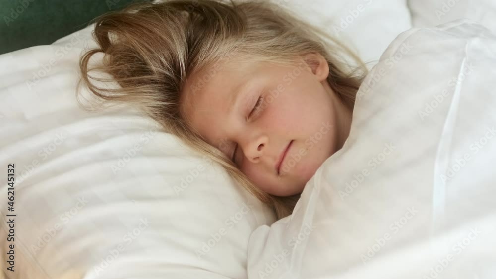 Little kid girl sleeping well in bed on pillow white linen orthopedic mattress. Relaxed child resting lying and enjoying healthy sleep nap in morning. Little kid girl sleeping well in bed on pillow white linen orthopedic mattress. Relaxed child resting lying and enjoying healthy sleep nap in morning.