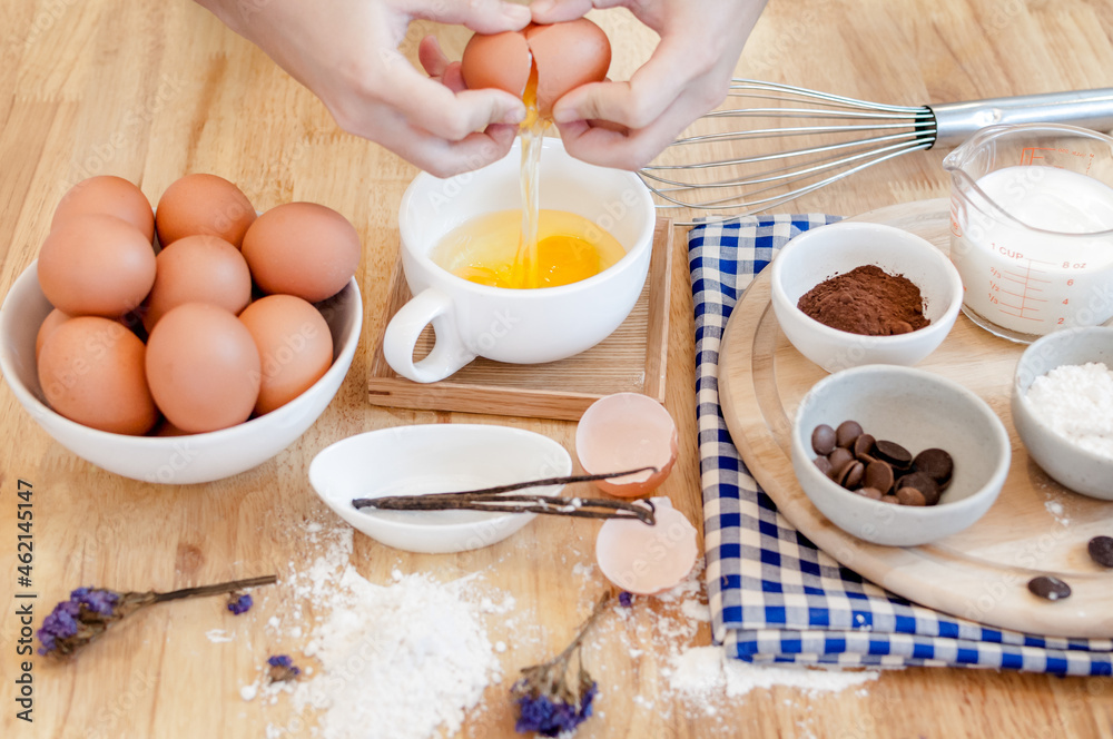 Man in the kitchen cooking a dough. Hands breaks an egg into a bowl ,hands pouring bitten egg ,Baking concept