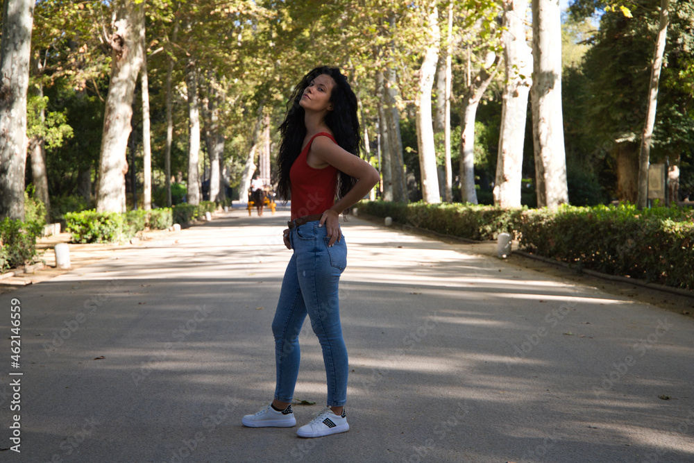 beautiful adult woman, brunette with curly hair and gypsy latin features is on a road and on the sides giant trees, the woman is making different gestures and poses. Concept expressions beautiful adult woman, brunette with curly hair and gypsy latin features is on a road and on the sides giant trees, the woman is making different gestures and poses. Concept expressions