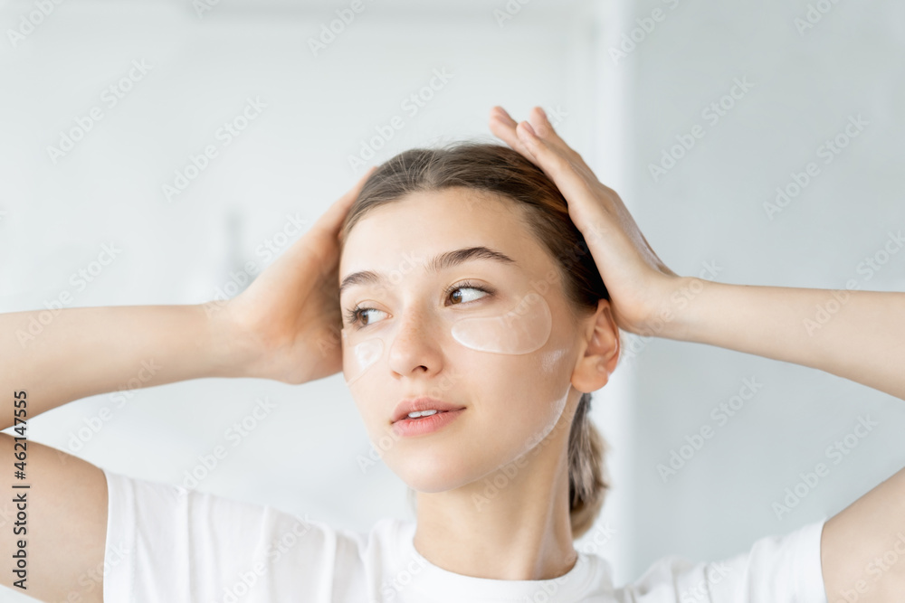 Facial skin care. Cosmetology treatment. Morning routine. Fresh young woman with under eye patches on flawless radiant face at bathroom. Facial skin care. Cosmetology treatment. Morning routine. Fresh young woman with under eye patches on flawless radiant face at bathroom.
