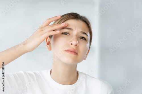 Wallpaper Mural Sensitive skin. Acne problem. Zit treatment. Frustrated young woman touching itchy dry face wrinkle on white defocused background. Torontodigital.ca