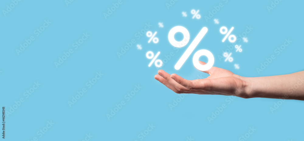Male hand holding interest rate percent icon on blue background. Interest rate financial and mortgage rates concept.Banner with copy space Male hand holding interest rate percent icon on blue background. Interest rate financial and mortgage rates concept.Banner with copy space