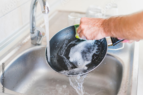 Man cleaning pan at sink in kitchen photo