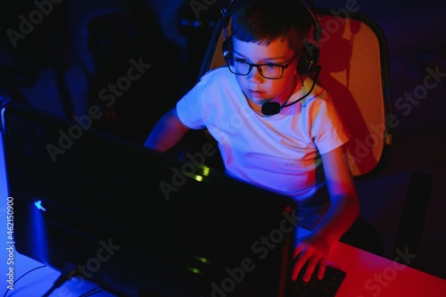 Professional Gamer Plays Video Game on His Computer. He's Participating in Online Cyber Games Tournament or in Internet Cafe. He Wears Glasses and Talks into Microphone. © Serhii