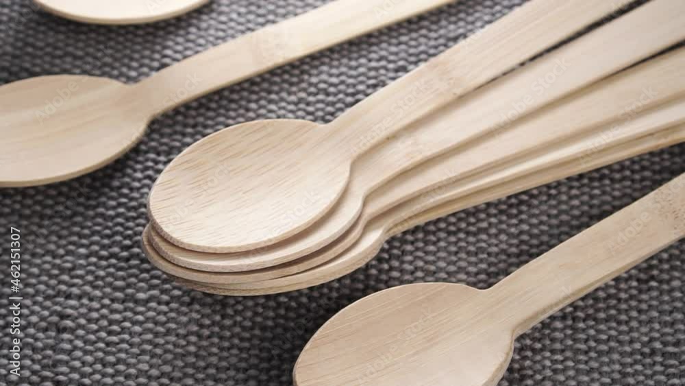 Organic biodegradable bamboo wooden spoon set falling on a textured natural burlap mat. Close up. Slow motion. Recycling eco-friendly concept Organic biodegradable bamboo wooden spoon set falling on a textured natural burlap mat. Close up. Slow motion. Recycling eco-friendly concept