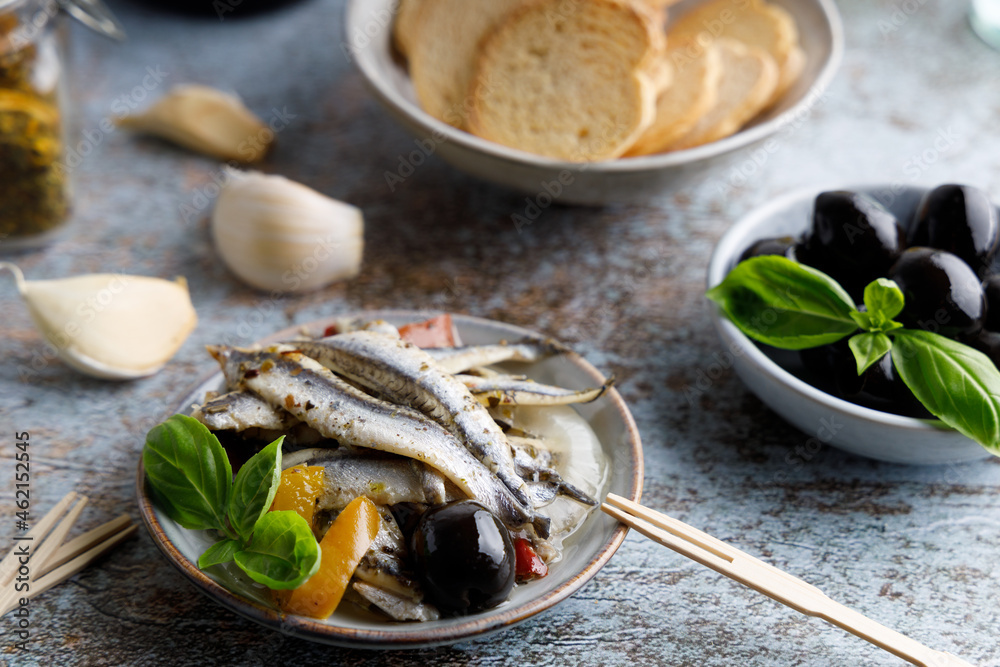 anchovy appetizer with olives. Mediterranean appetizer, anchovy fish in olive oil and herbs in a small bowl. Top down view. anchovy appetizer with olives. Mediterranean appetizer, anchovy fish in olive oil and herbs in a small bowl. Top down view.