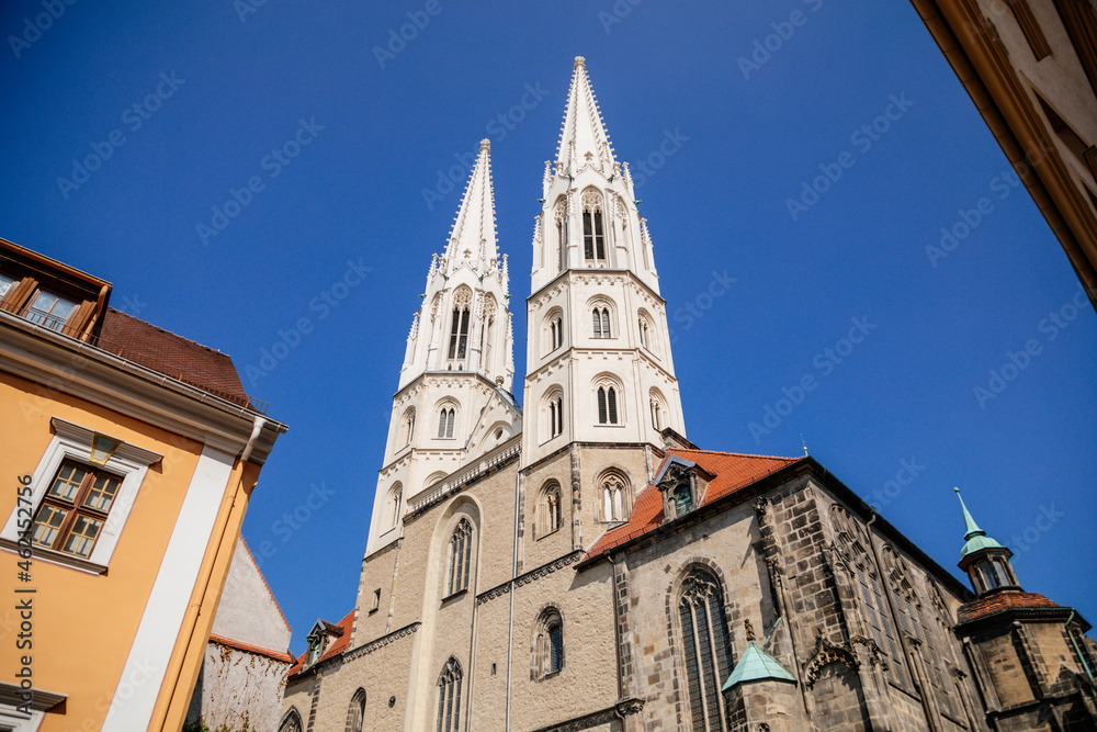 Goerlitz, Germany, 04 September 2021: gothic medieval St. Peter and Paul Church or Peterskirche with two white towers in historical center of city near river at sunny summer day, arched portal