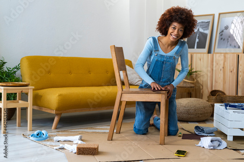 Redhead woman polishing wooden chair while kneeling on cardboard photo