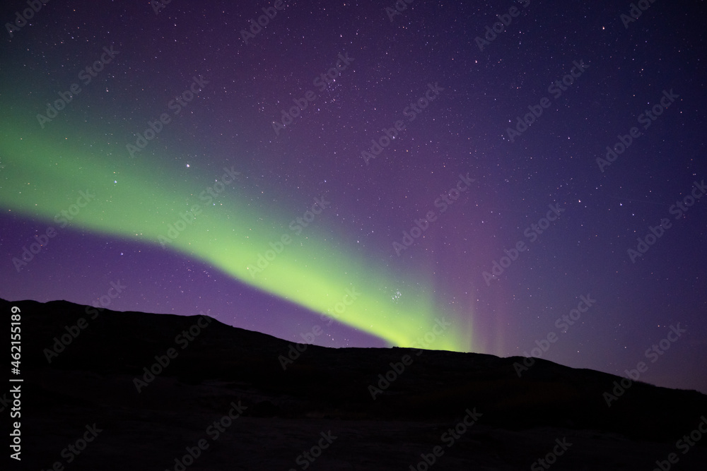 Bright green nortern lights on the shore of Barents sea in Teriberka