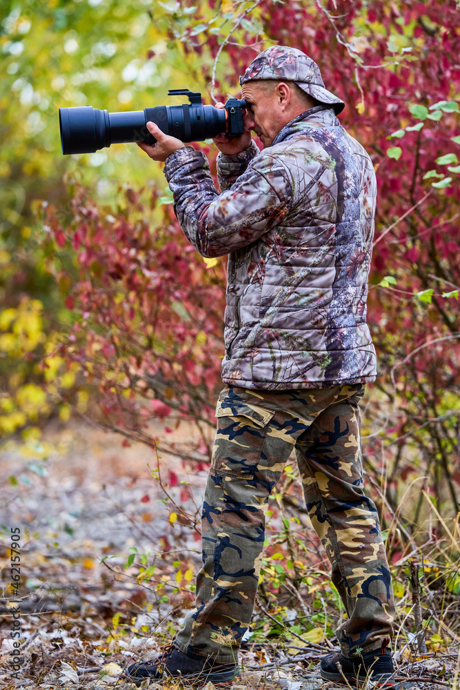 Naklejka premium professional photographer in camouflage clothes working in nature.