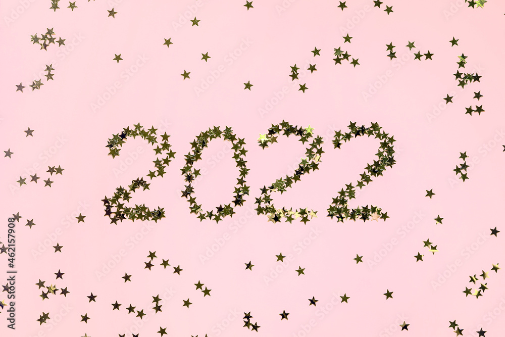 Numbers 2022 from gold stars spangles on pink background. Creative Christmas and New Year holiday concept. Numbers 2022 from gold stars spangles on pink background. Creative Christmas and New Year holiday concept.