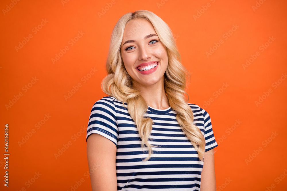 Portrait of attractive cheerful girl wearing striped tshirt beaming smile isolated over vibrant orange color background