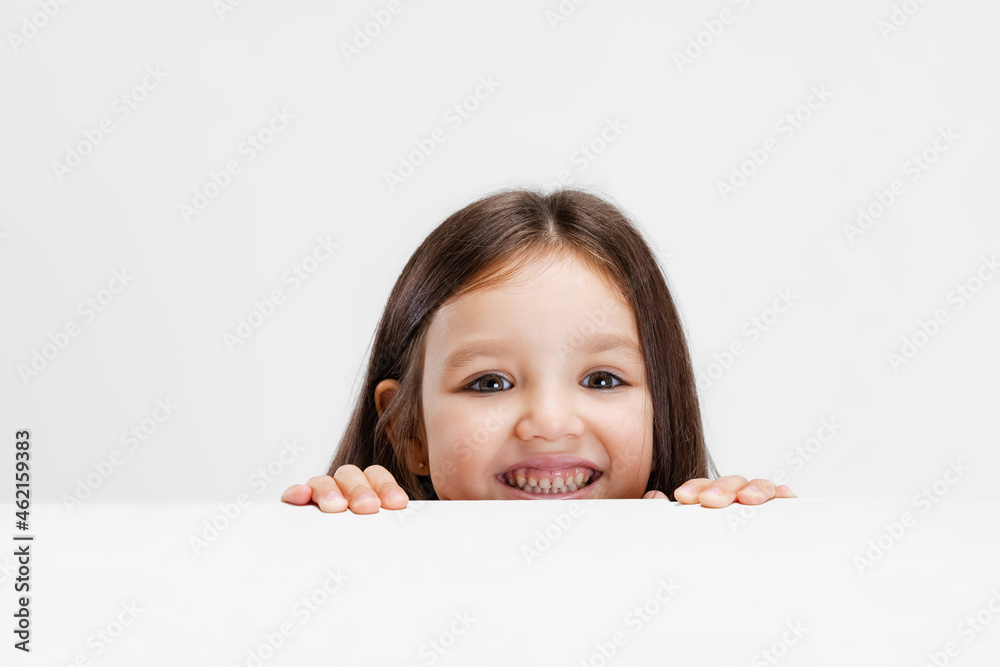One cute beautiful little girl playing isolated on white studio background. Human emotions, facial expression concept. One cute beautiful little girl playing isolated on white studio background. Human emotions, facial expression concept.