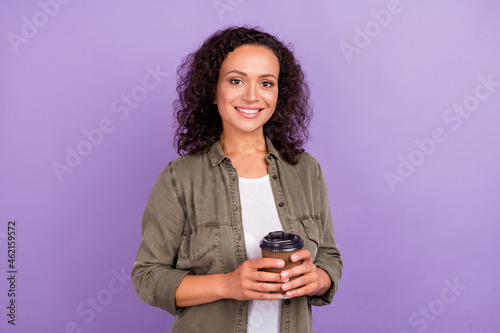 Photo of cheerful young positive afro american woman hold hands takeaway coffee cup isolated on violet color background