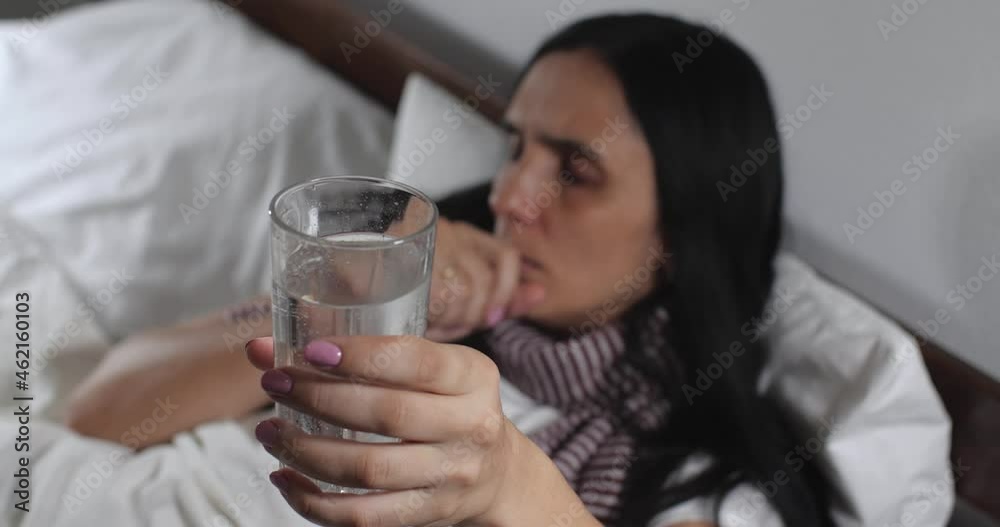 Extreme close up of caucasian brunette with long black hair caught a cold lying in bed with white linens in light room suffering from flu. Attractive woman coughing and sneezing , taking pills Extreme close up of caucasian brunette with long black hair caught a cold lying in bed with white linens in light room suffering from flu. Attractive woman coughing and sneezing , taking pills