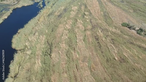 Deep blue waters of Kwando river that splits in to in the distance with long grass of wetlands all-around camera panning up Aerial Video. Kwando River, Mudumu, Caprivi, Namibia photo