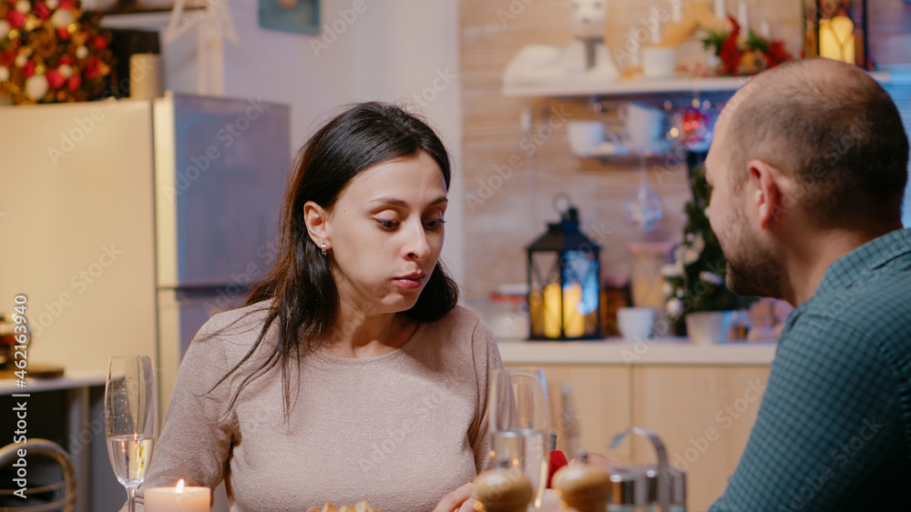 Close up of cheerful woman getting asked to marry partner at christmas eve dinner. Man proposing to young adult with engagement ring while enjoying festive meal. Engaged couple on holiday
