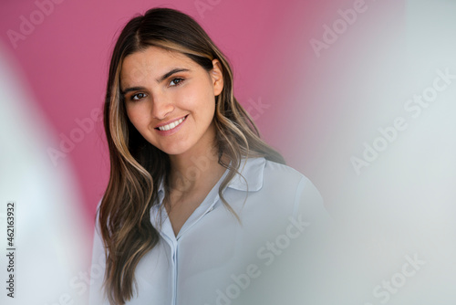 Smiling female business professional with brown hair in front of wall
