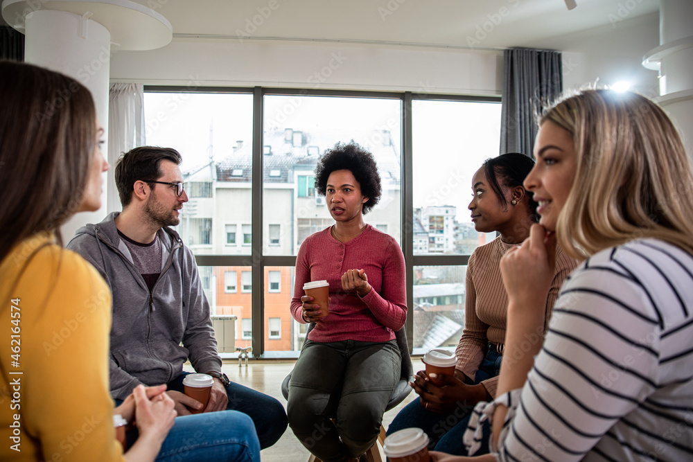 Diverse group of people sitting in circle in group therapy session.