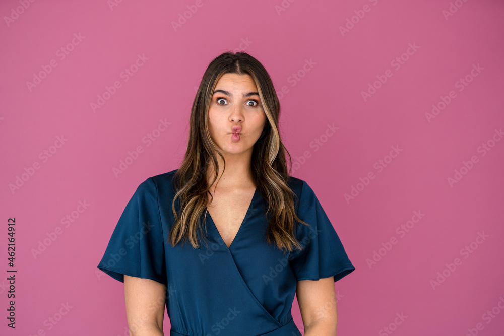 Businesswoman making face in front of pink wall Businesswoman making face in front of pink wall