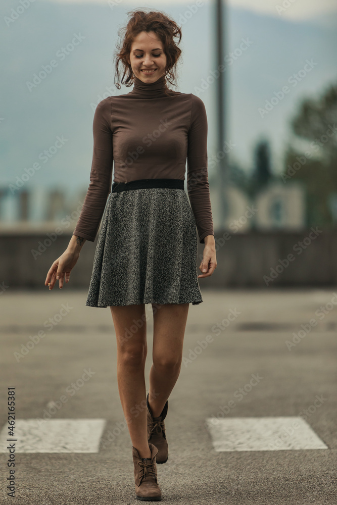 Trendy young woman crossing the street with a happy smile