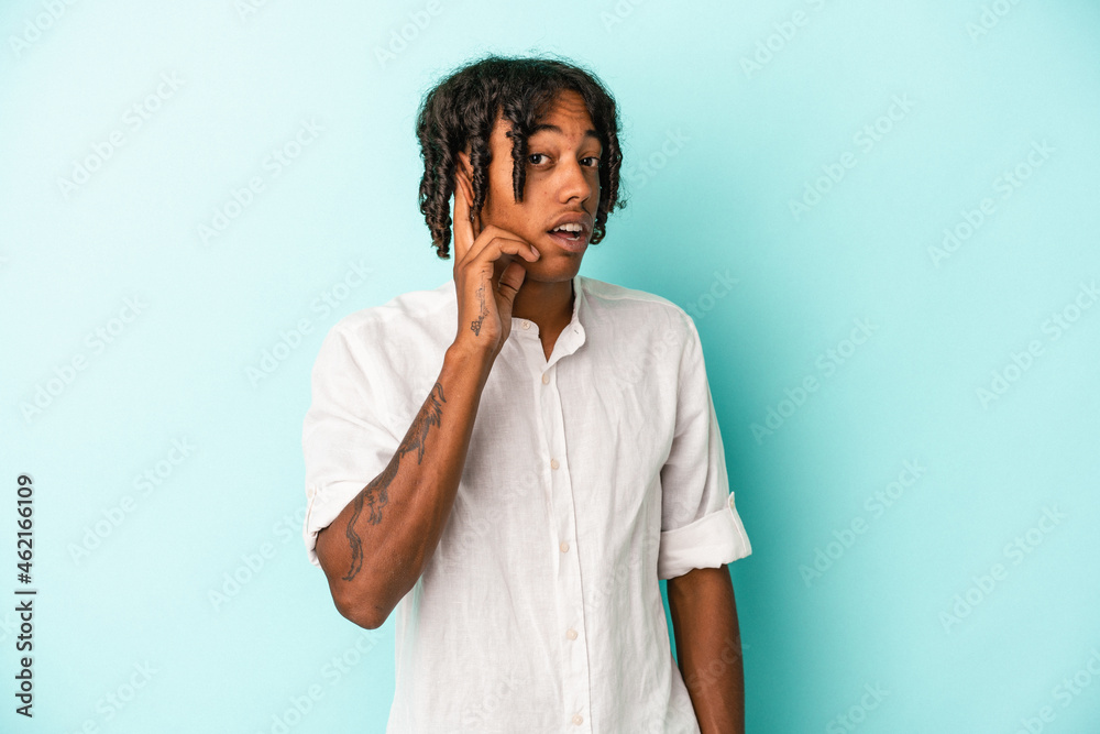 Young african american man isolated on blue background trying to listening a gossip.
