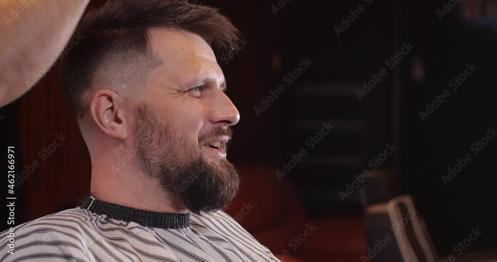 Close-up of a handsome Caucasian guy sitting in a hairdressing salon. An unrecognizable barber brushes off bobbed hair and makes styling. 4K 50 fps slow motion Close-up of a handsome Caucasian guy sitting in a hairdressing salon. An unrecognizable barber brushes off bobbed hair and makes styling. 4K 50 fps slow motion