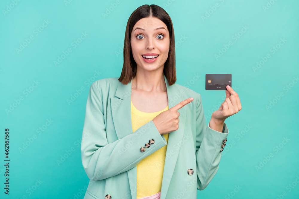Photo of impressed millennial brunette lady point card wear jacket isolated on cyan color background Photo of impressed millennial brunette lady point card wear jacket isolated on cyan color background